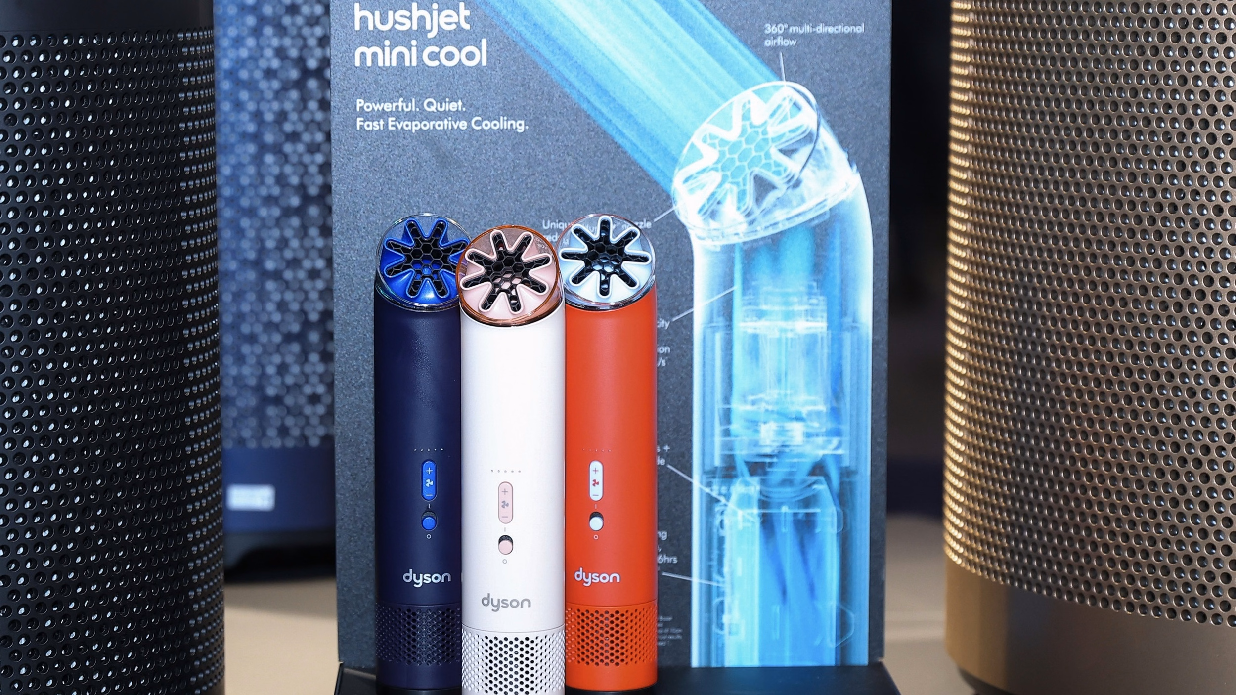 Dyson HushJet Mini Cool Fan สามสีวางเรียงหน้าป้ายโฆษณา